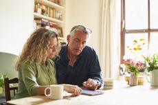 Couple sitting at table using digital tablet