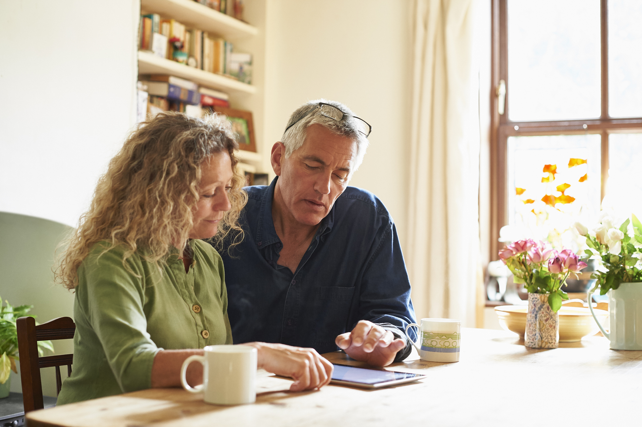 Couple sitting at table using digital tablet 