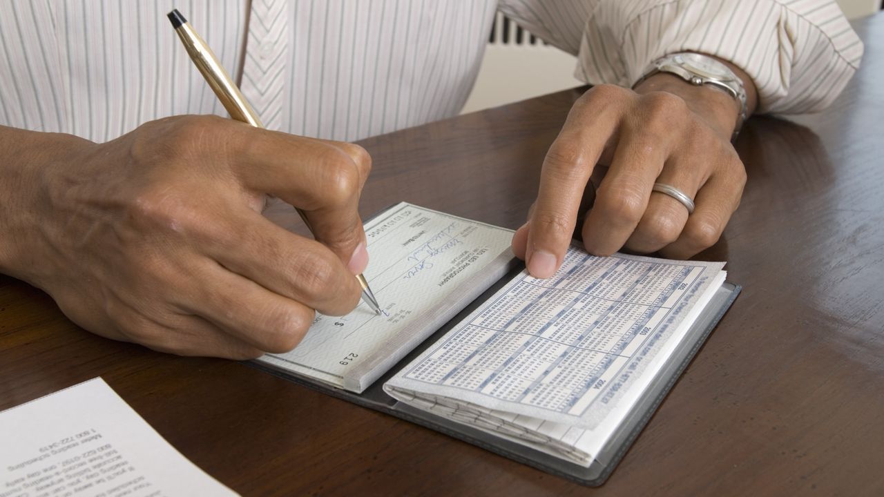 A man writes a personal check.