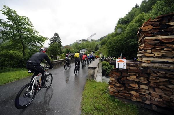 Riders pass in front of the Garmisch Partenkirchen ski jump.