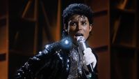 Jafaar Jackson performing as Michael Jackson in glittery black suit and wearing a sequined glove while holding a microphone