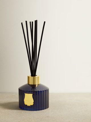A reed diffuser with black reeds and a black glass jar
