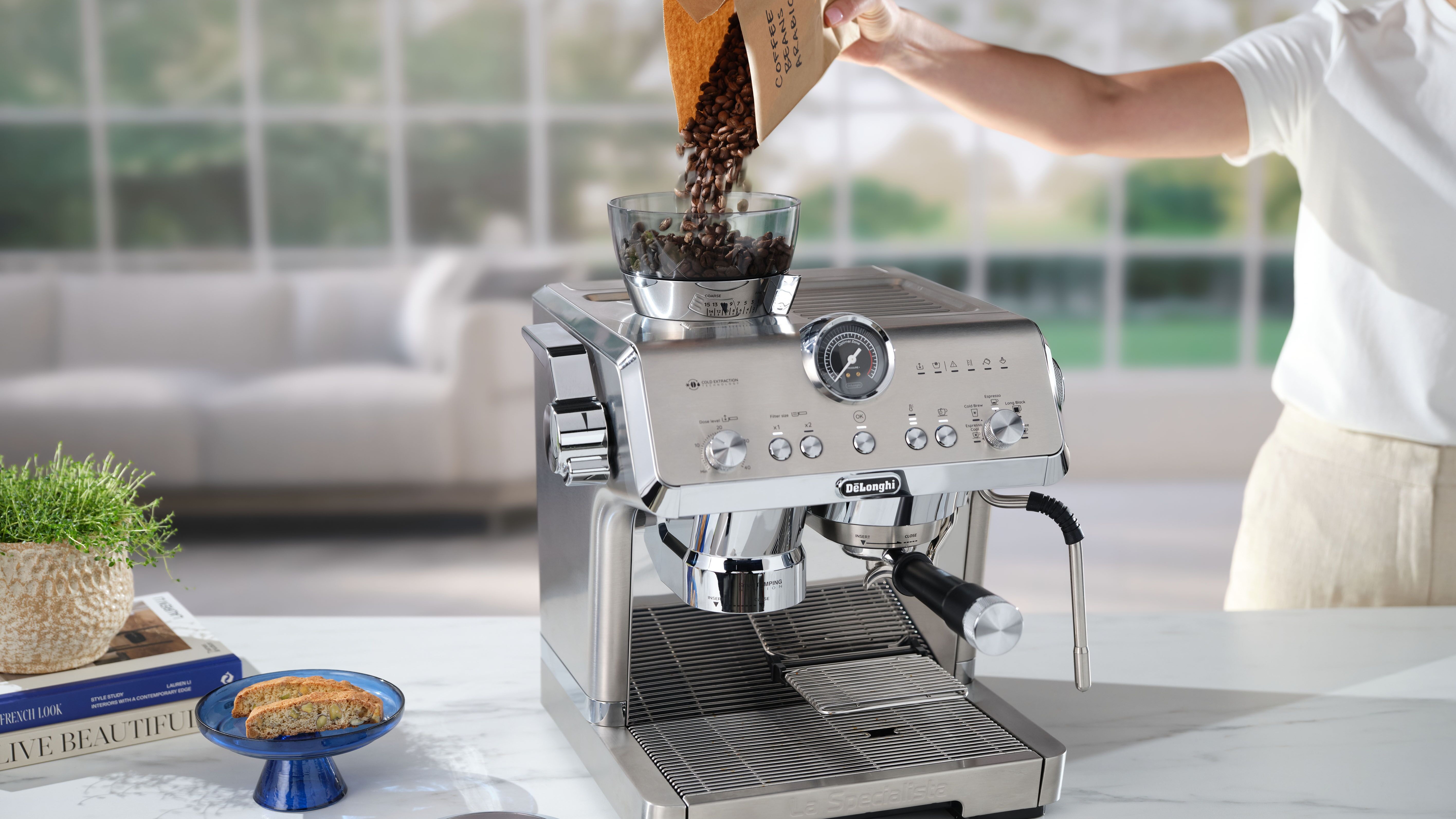 Woman pouring coffee beans into De'Longhi La Specialista Opera coffee maker