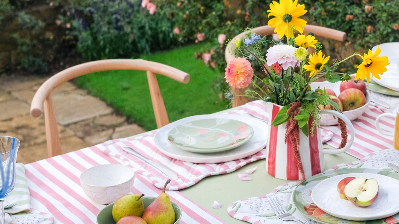 table with pink striped tablecloth, striped jug with fresh flowers and apples