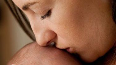 mother holding and kissing baby