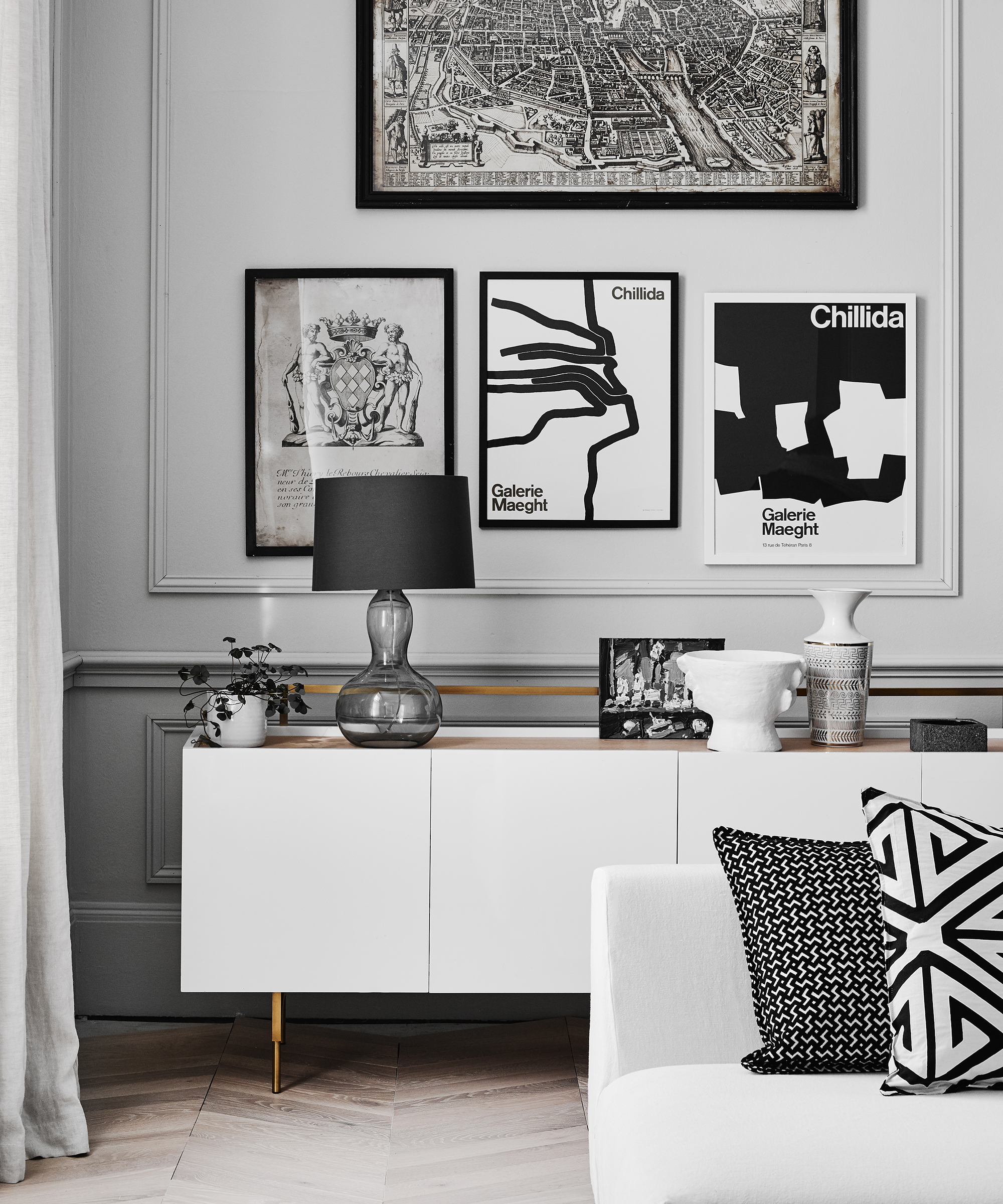 A monochrome living room with white sideboard and artwork display.