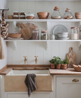 Rustic open shelving above a stoneware sink in a white kitchen