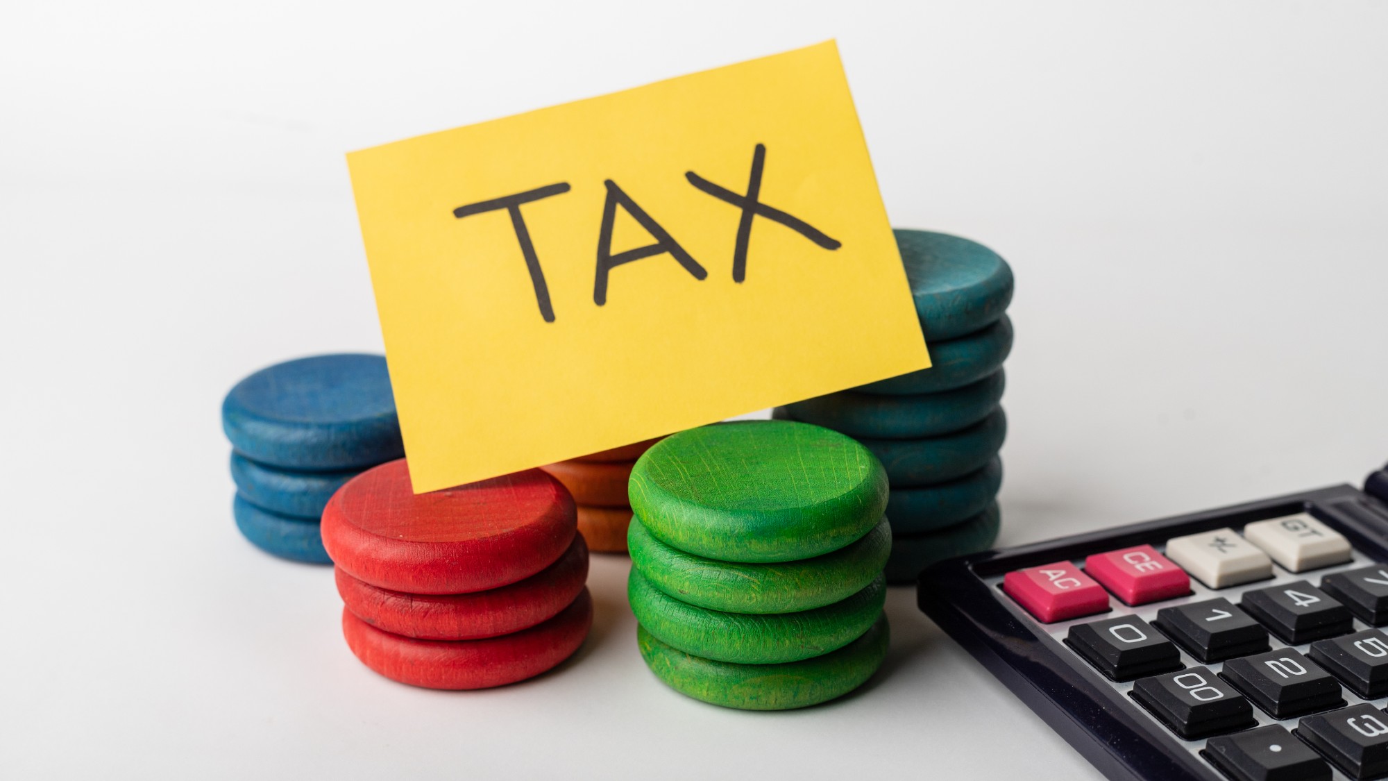 photo of "tax" written on a yellow note card, and sitting on top of a collection of brightly colored tokens