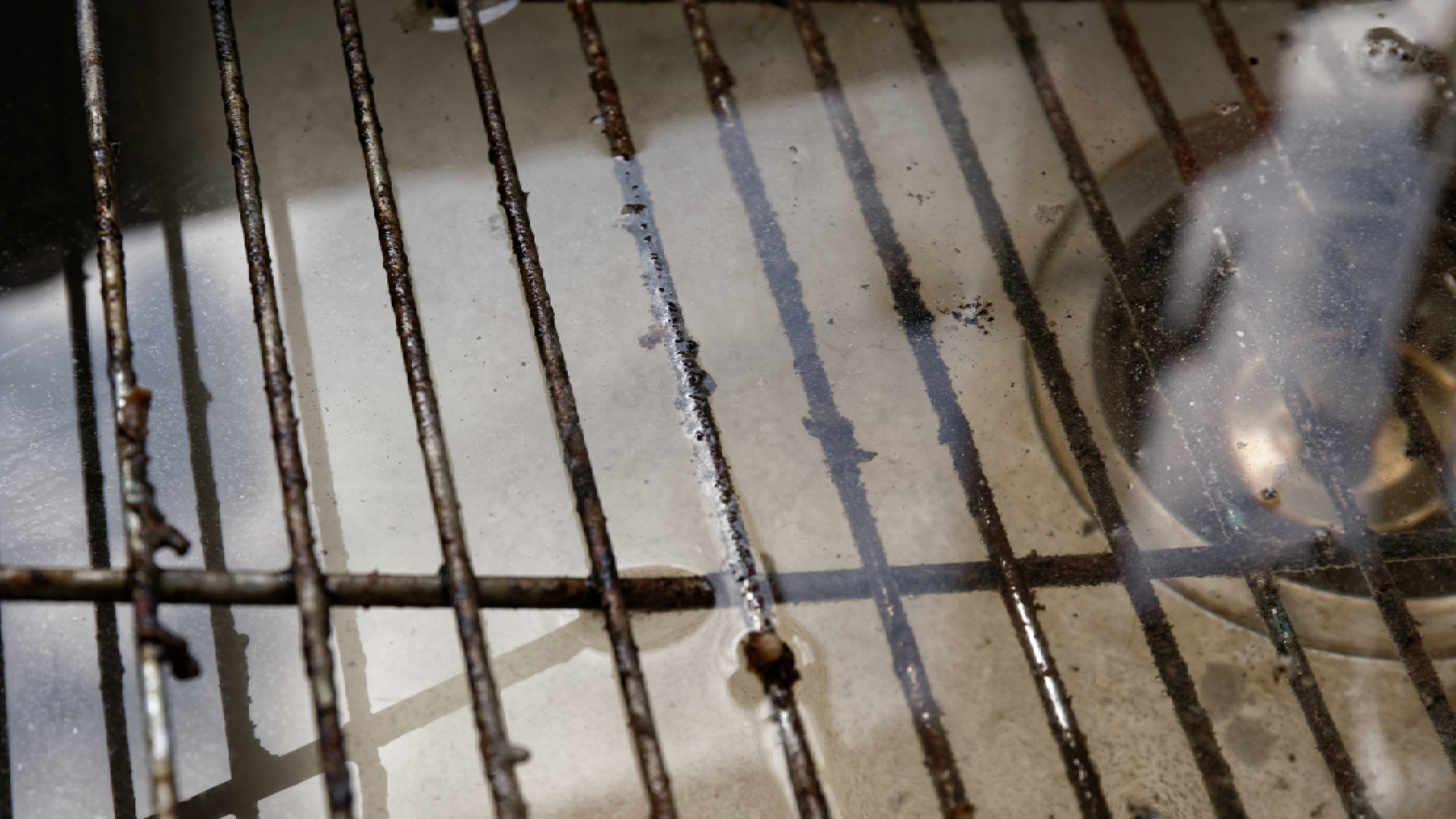 Grimy grill rack submerged in sink