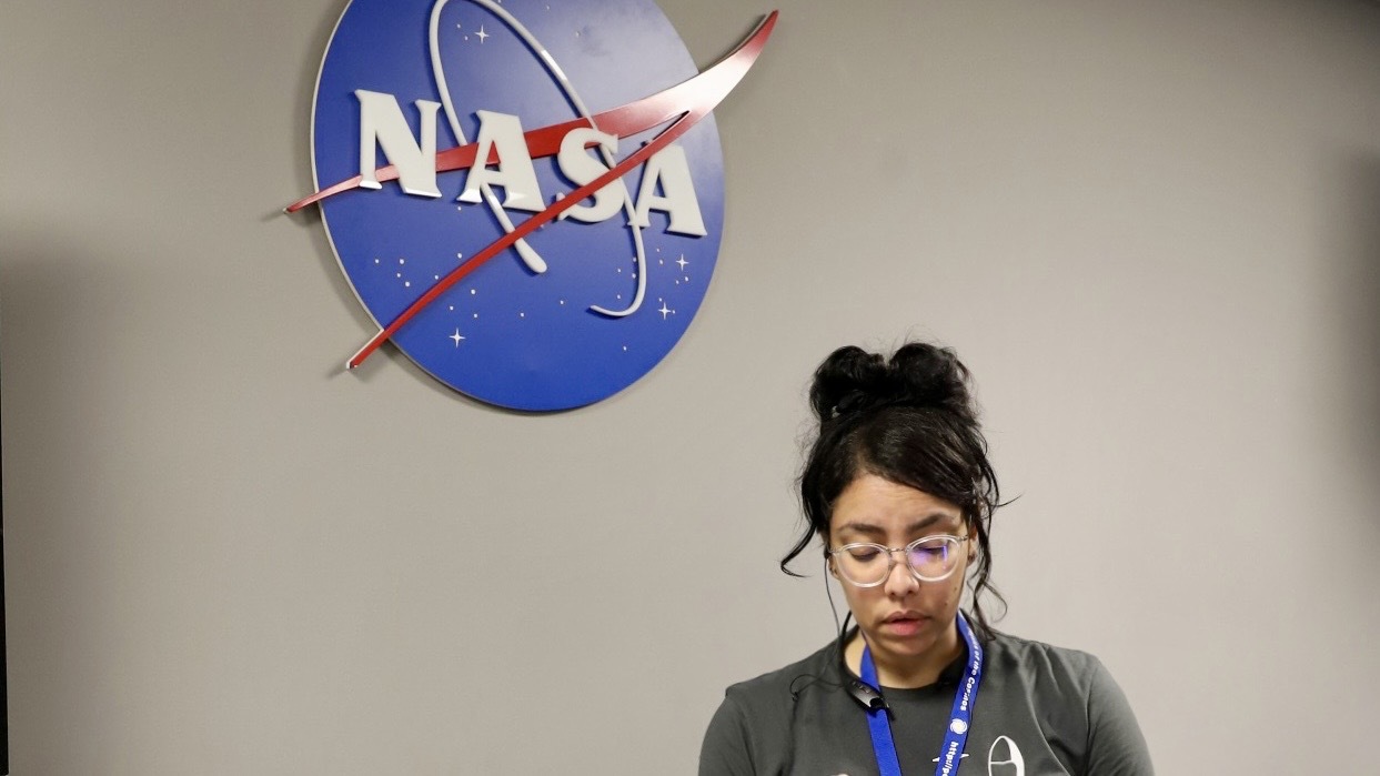 a woman stands beneath a nasa logo