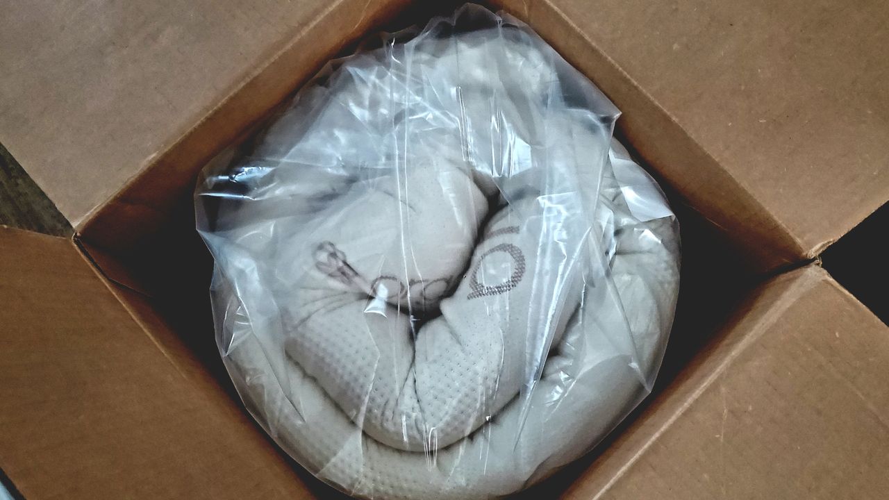 The Saatva Foam Mattress Topper rolled up inside an opened shipping box