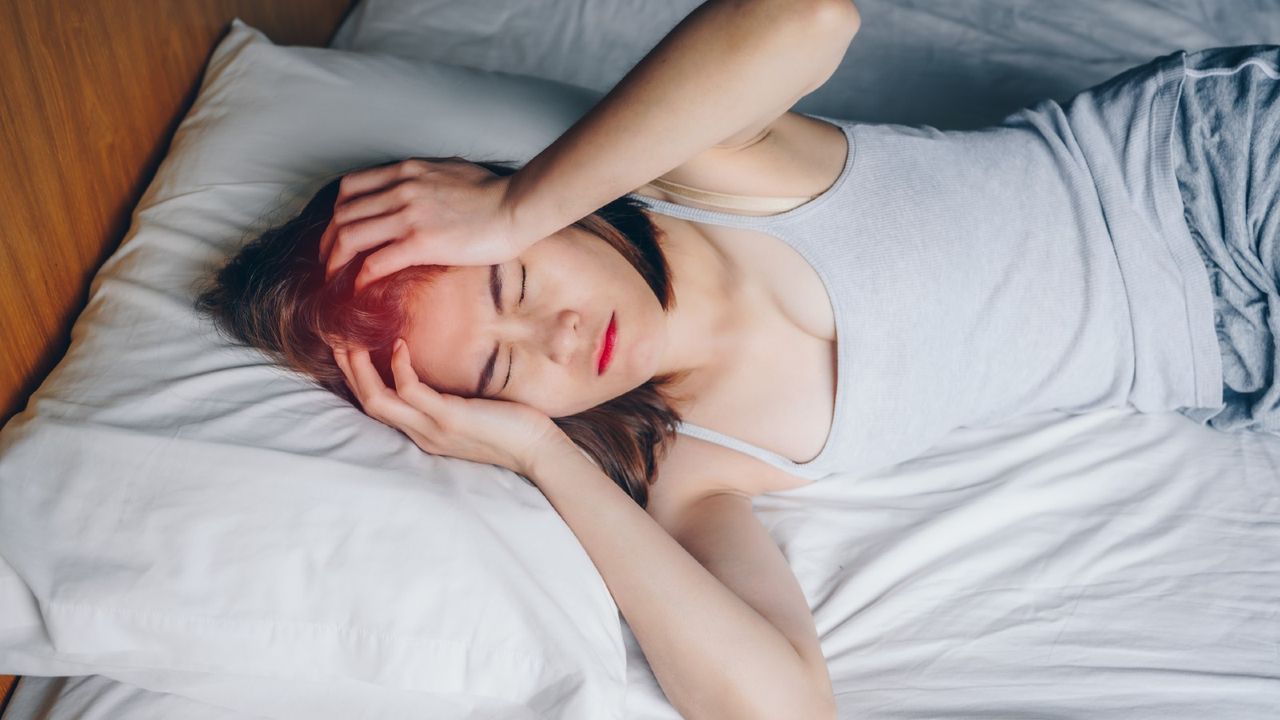 Woman suffering from a hangover while she lying on bed