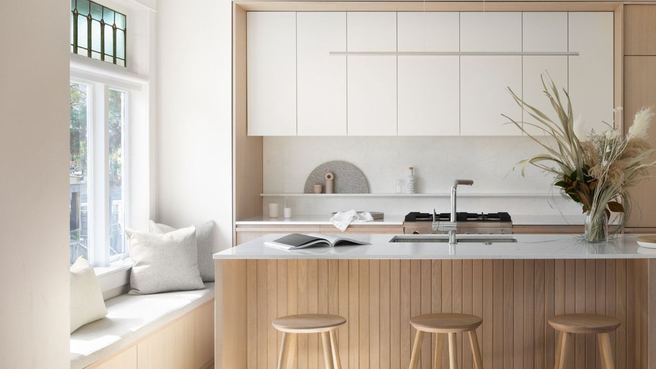 A kitchen with bar chairs by the island. A book sits on top of the island