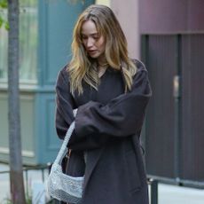 Jennifer Lawrence wears black satin kitten heels with a brown coat and a silver sparkly bag.
