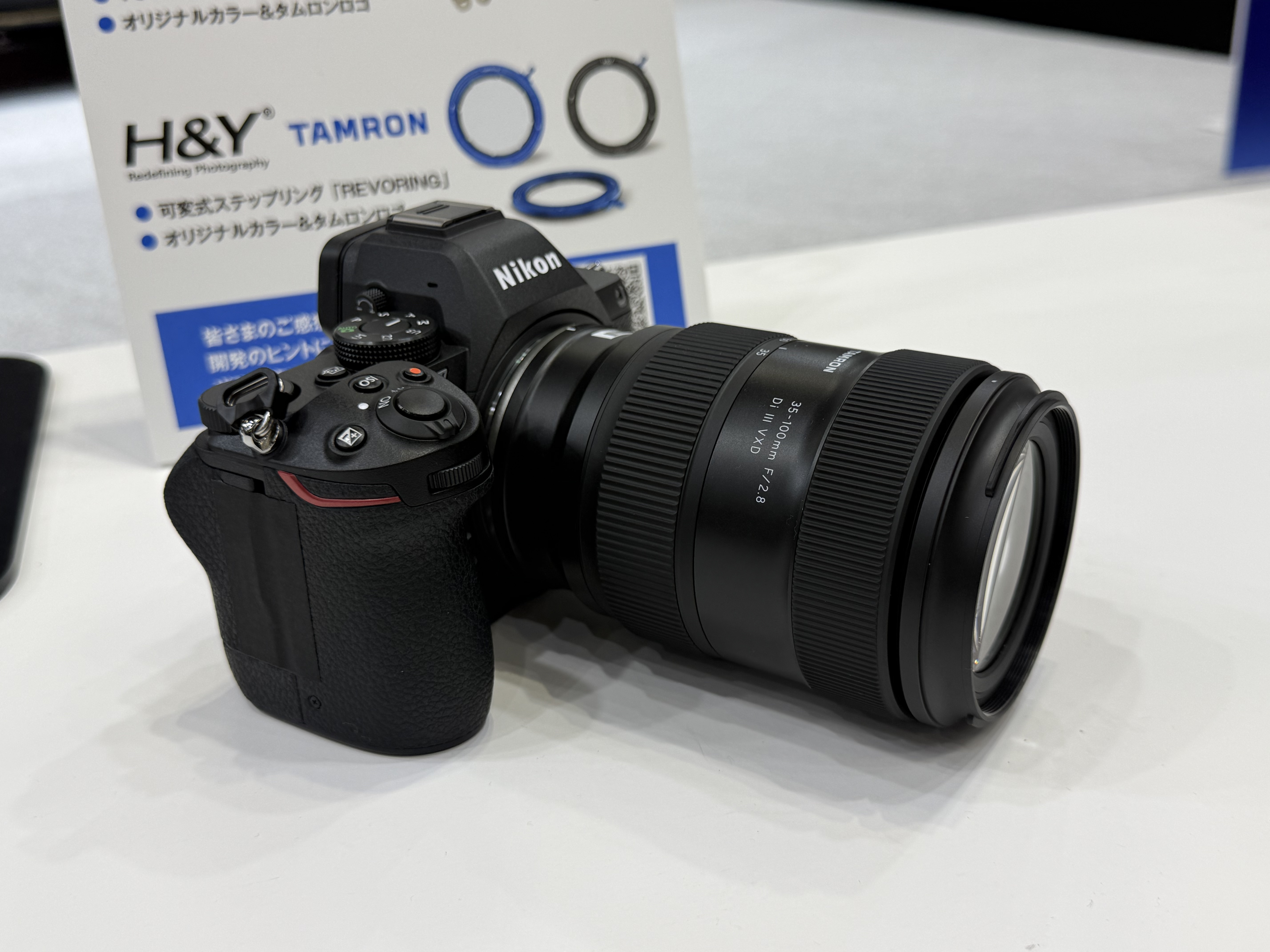 The Tamron 35-100mm f/2.8 zoom lens attached to a Nikon camera, on display at the CP+ 2026 show