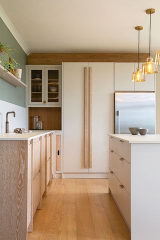 scandi kitchen with limed cabinetry with white larder and wooden flooring