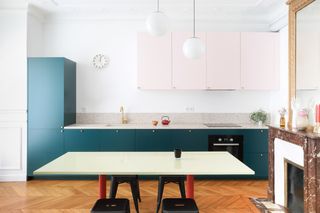 A kitchen with pink upper cabinets and dark green lower cabinets