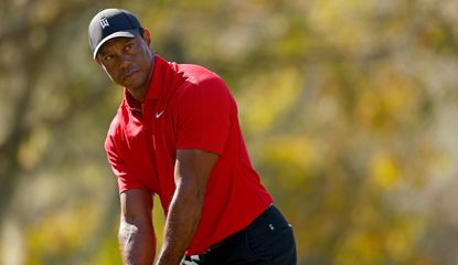 Tiger Woods eyes up his tee shot whilst wearing his Sunday Red clothing