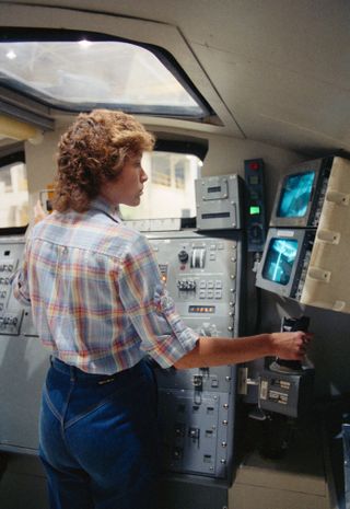 During STS-51A shuttle mission in 1980, astronaut Anna Fisher flew the space shuttle Discovery's robotic arm to support the retrieval of two malfunctioning satellites, and the deployment of two new communications satellites. Seen here, Fisher practices ro