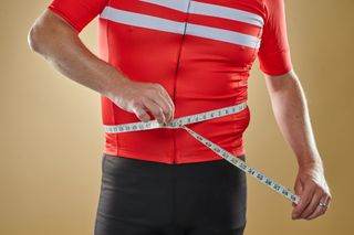 Male cyclist measuring himself with a measuring tape