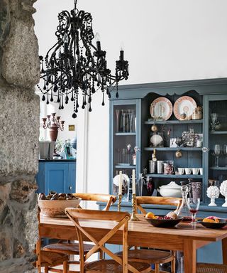 White dining room with black chandelier and blue painted dresser