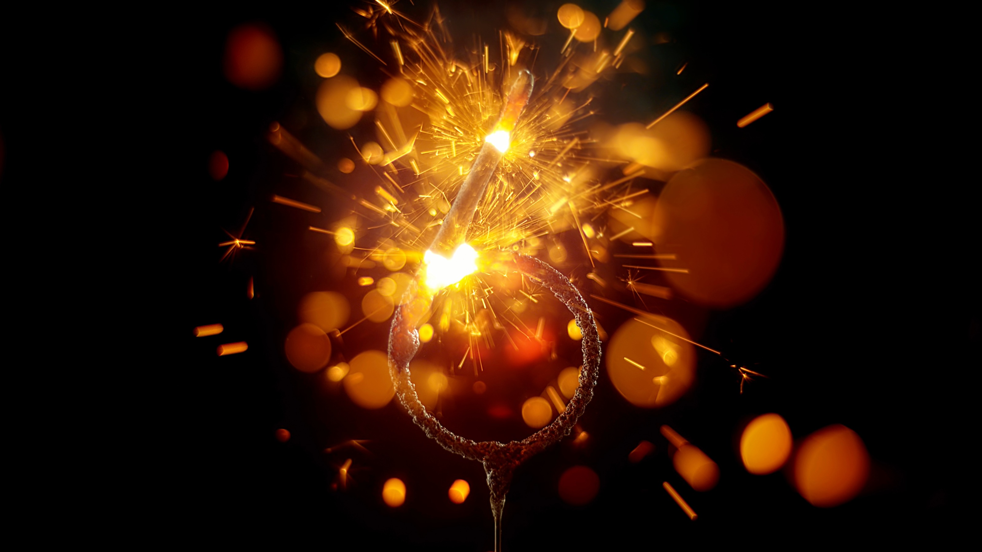 Close-up of sparkler in shape of 'NUMBER 6' emitting sparks while burning against black background