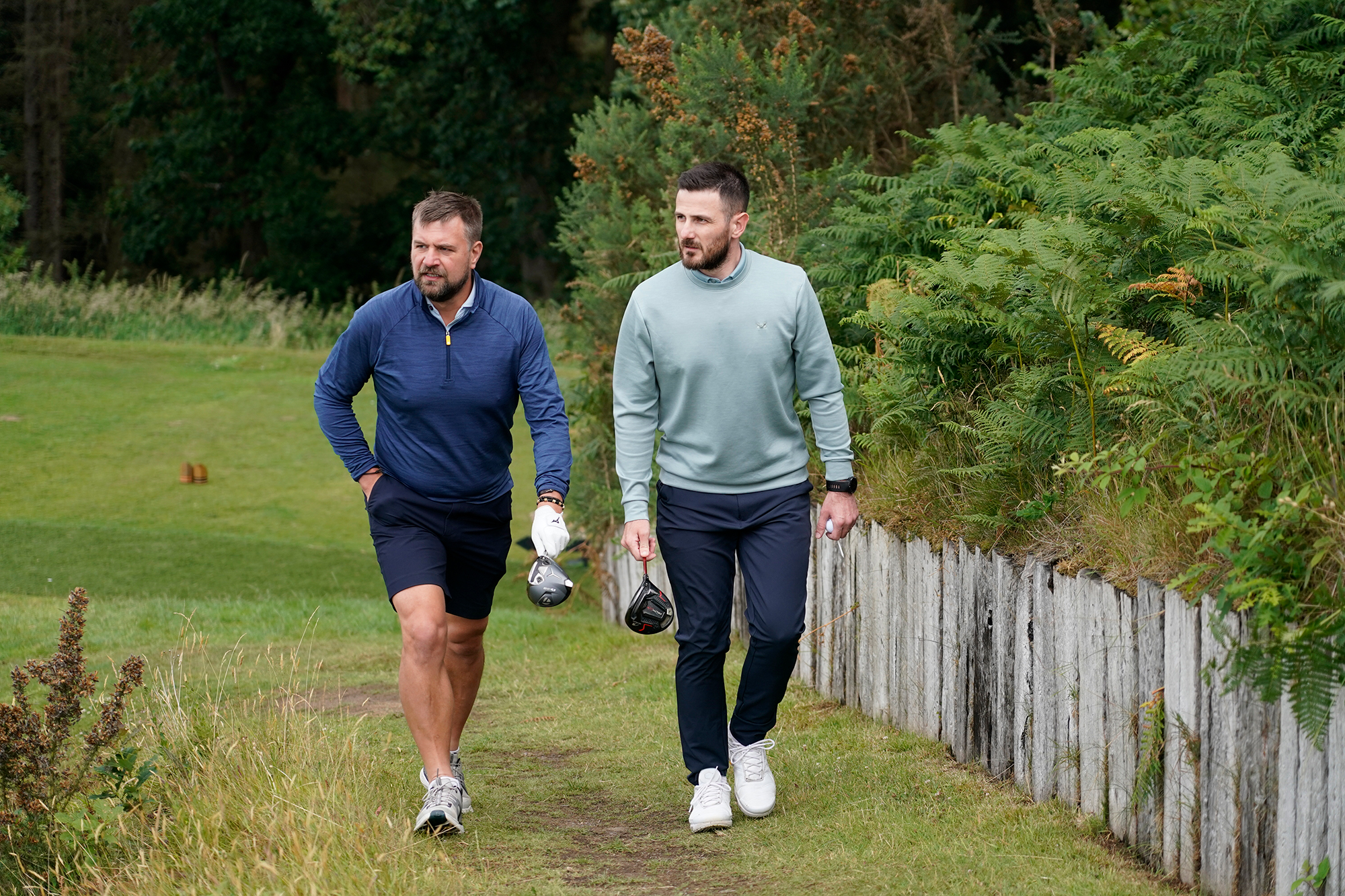 Baz Plummer and Sand Moor Golf Club Head Pro Alex James walking on the golf course, holding their driver on the way to the tee box