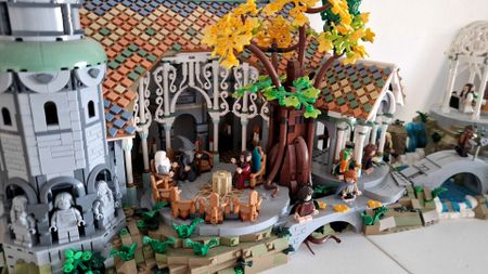 Lego Rivendell and minifigures on a white surface, against a plain background