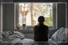A child pictured from behind looking out a bedroom window