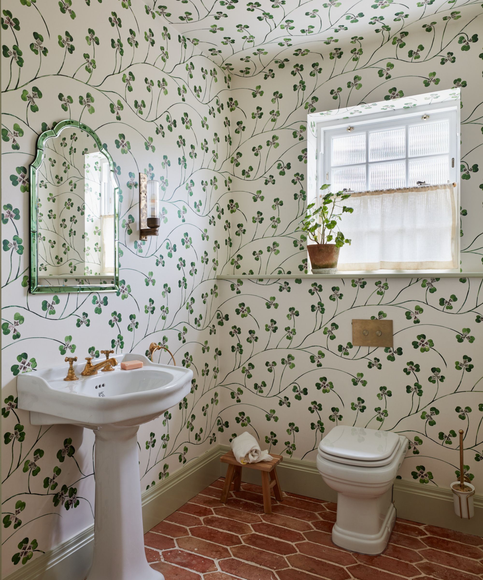 small bathroom with ivy print wallpaper and terracotta floor