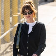 Dakota Johnson leaving "Jimmy Kimmel Live!" on June 19, 2024 wearing a black cardigan with baggy jeans, a Gucci belt, a Gucci Jackie bag, and white Gucci kitten heels.