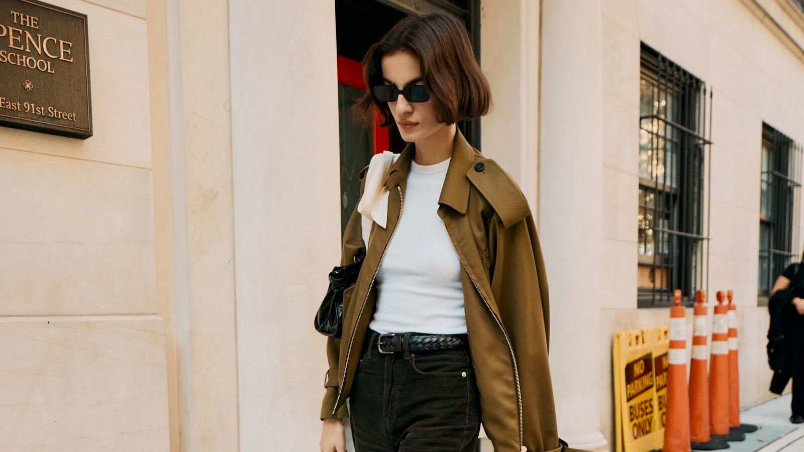 Woman in black jeans, white crewneck, and cropped trench.