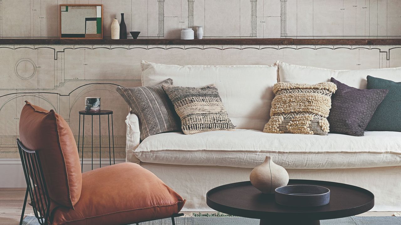 A living room with a loose-cover cream sofa with contrasting scatter cushions and a wall mural