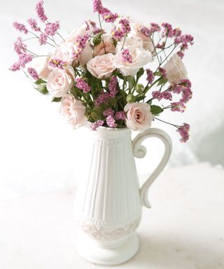 Pink flowers in a white jug vase