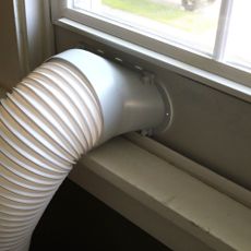 Exhaust tube of a portable air conditioner vented out of a sash window with window kit in place