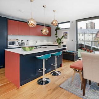 Kitchen with dark navy and orange-red cabinetry, breakfast bar and metallic orb lights