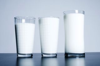 Three glasses of milk sit on a table.