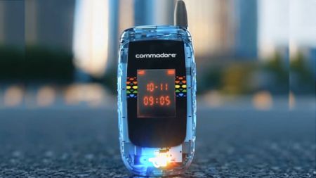 Transparent Commodore Callback 8020 flip-phone with clamshell closed sitting outside on ground with blurred backdrop.