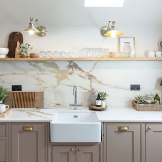 taupe Shaker kitchen with marble splashback and worktops and Belfast sink with open kitchen shelving