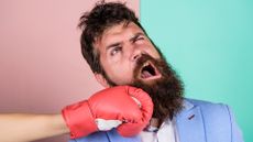 A man with a beard takes a punch to the jaw.