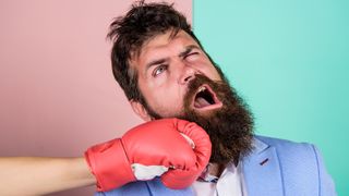 A man with a beard takes a punch to the jaw.