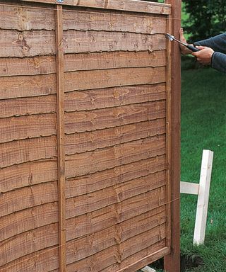 man attaching a fence panel to a freshly installed fence post