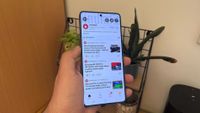 A hand holding a smartphone with the What Hi-Fi? official Reddit page on screen