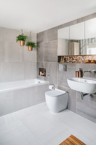 grey bathroom with large format tiles, built in bat hand copper accents