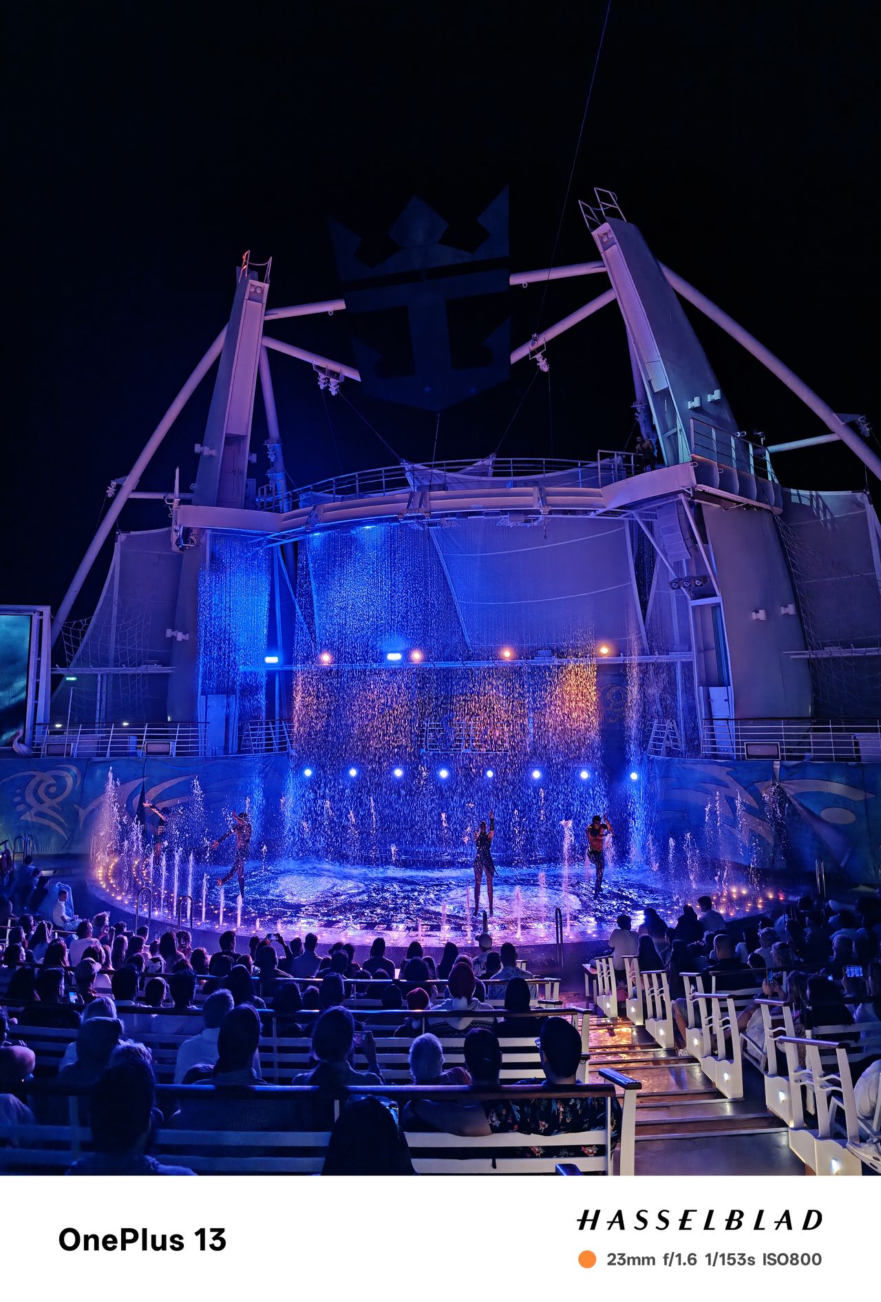 People performing a water show on a cruise ship at night lit by blue lights