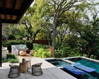 An outdoor space with a small pool, a seating area and lush greenery
