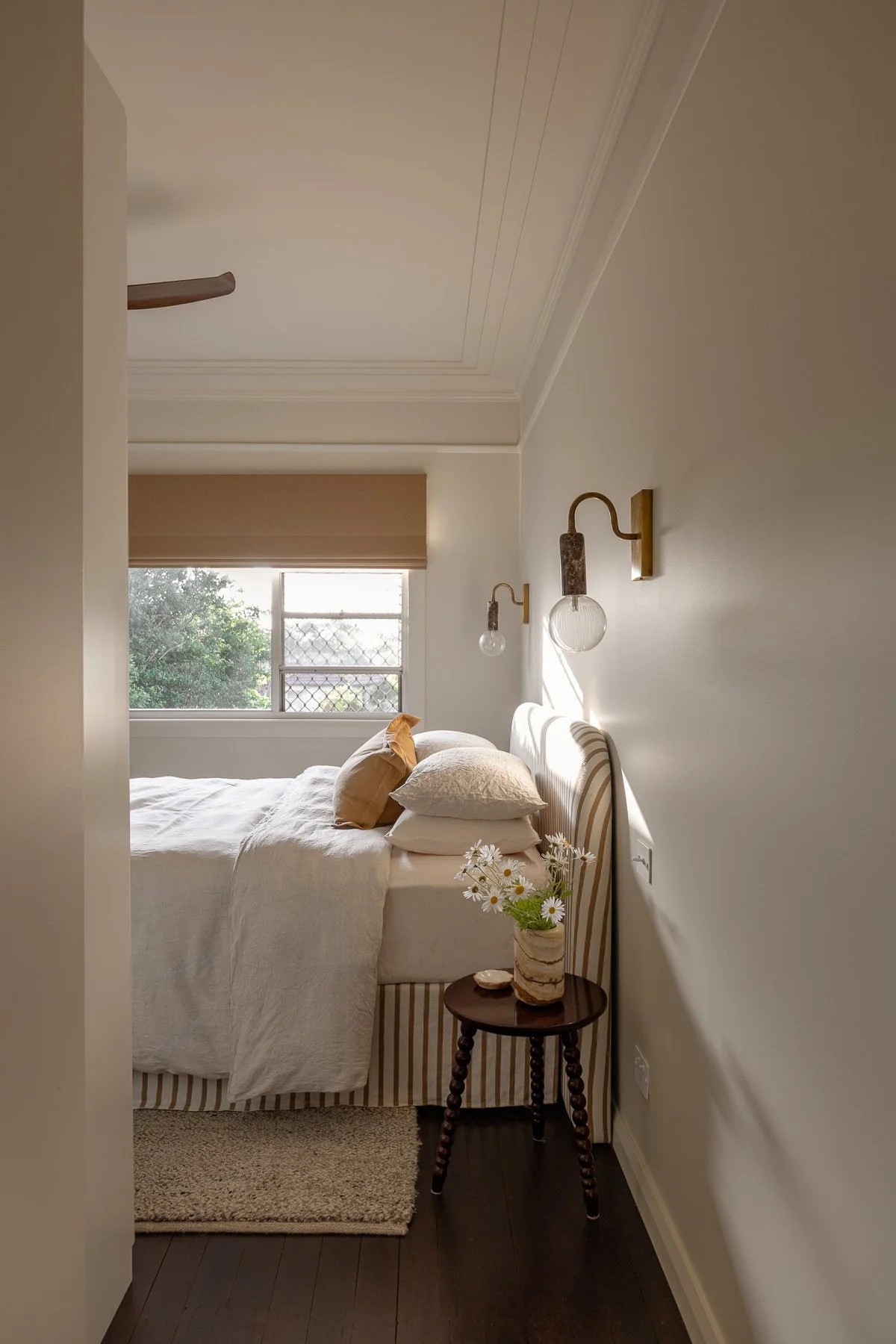 White bedroom with a white striped bed valance and white bedding.