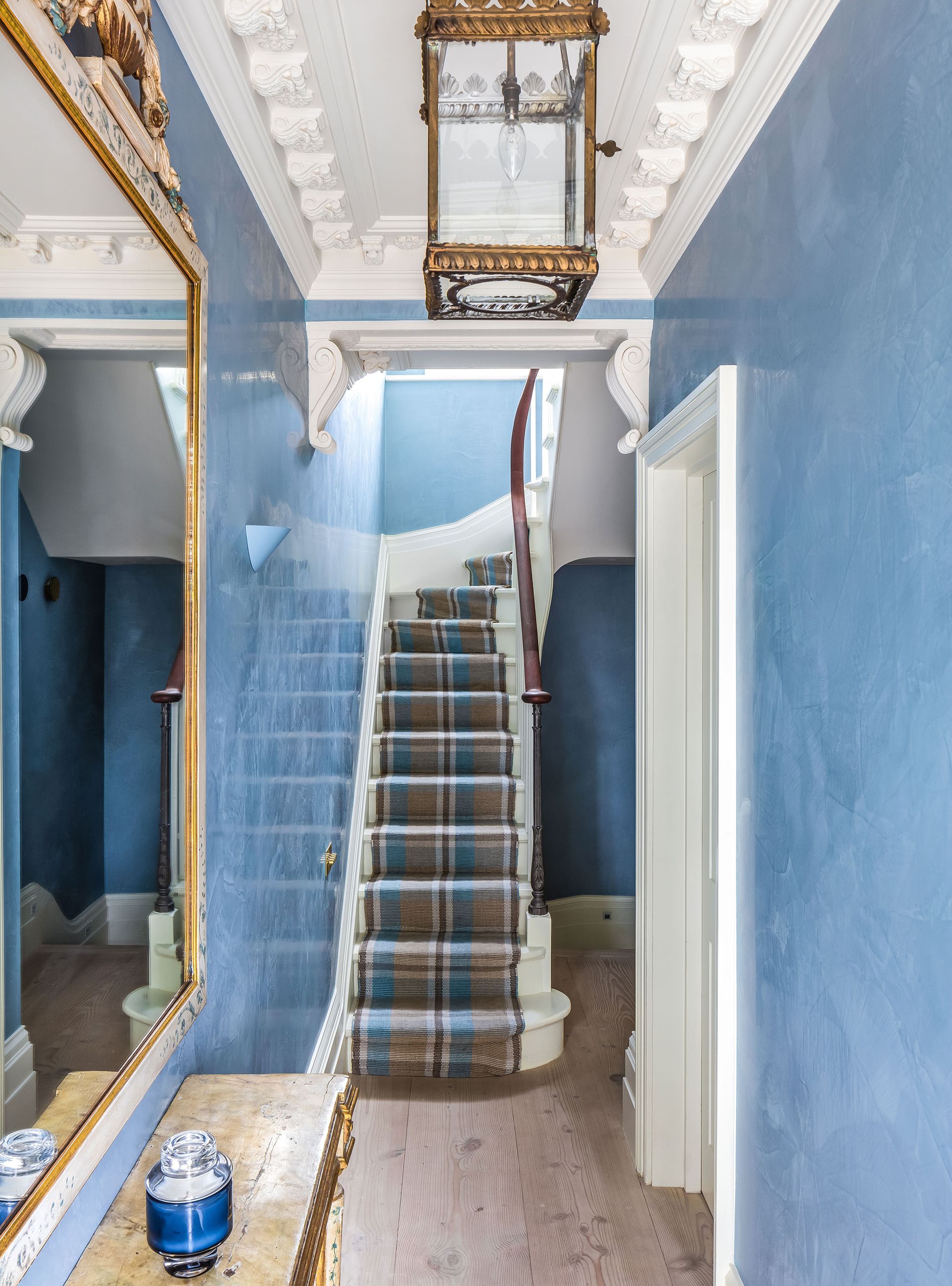 blue hallway with antique mirror and light fixture