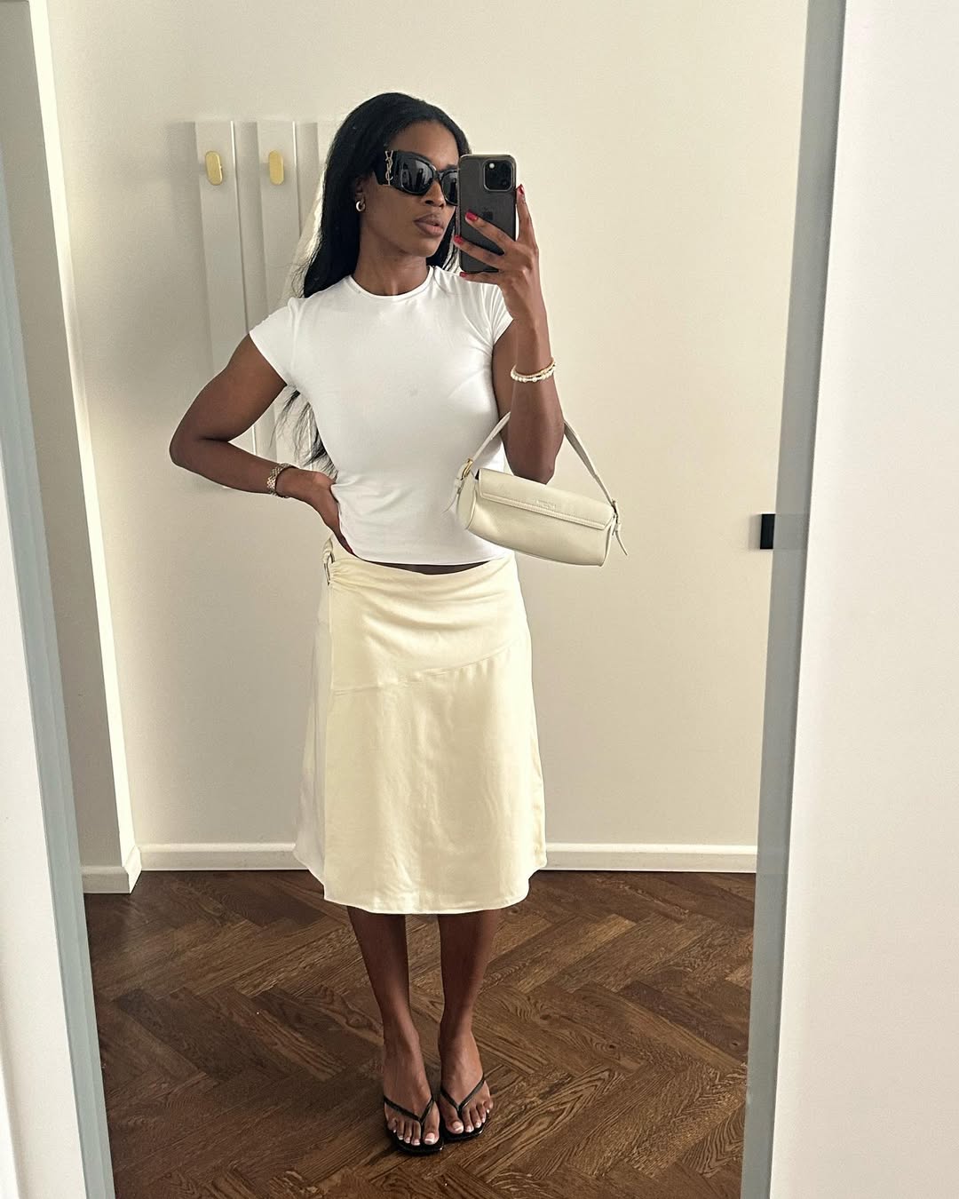 Woman wearing white t-shirt and knee-length skirt summer 2025.