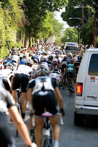 Chaos on the Manayunk Wall as the women's peloton overtakes vehicles at the tail end of the men's race caravan.